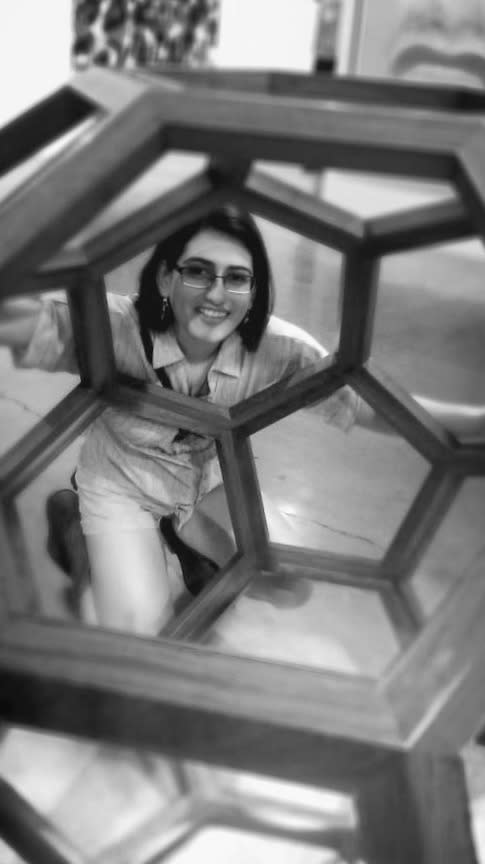 Black and white photo of a woman looking through a buckyball. 